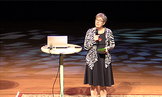 Bild på Agneta Jansmyr som står på scen och föreläser