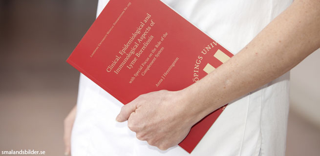 Bild på en person som håller en röd bok