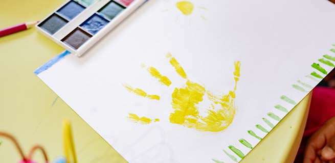Ett vitt papper med en målad gul hand på.